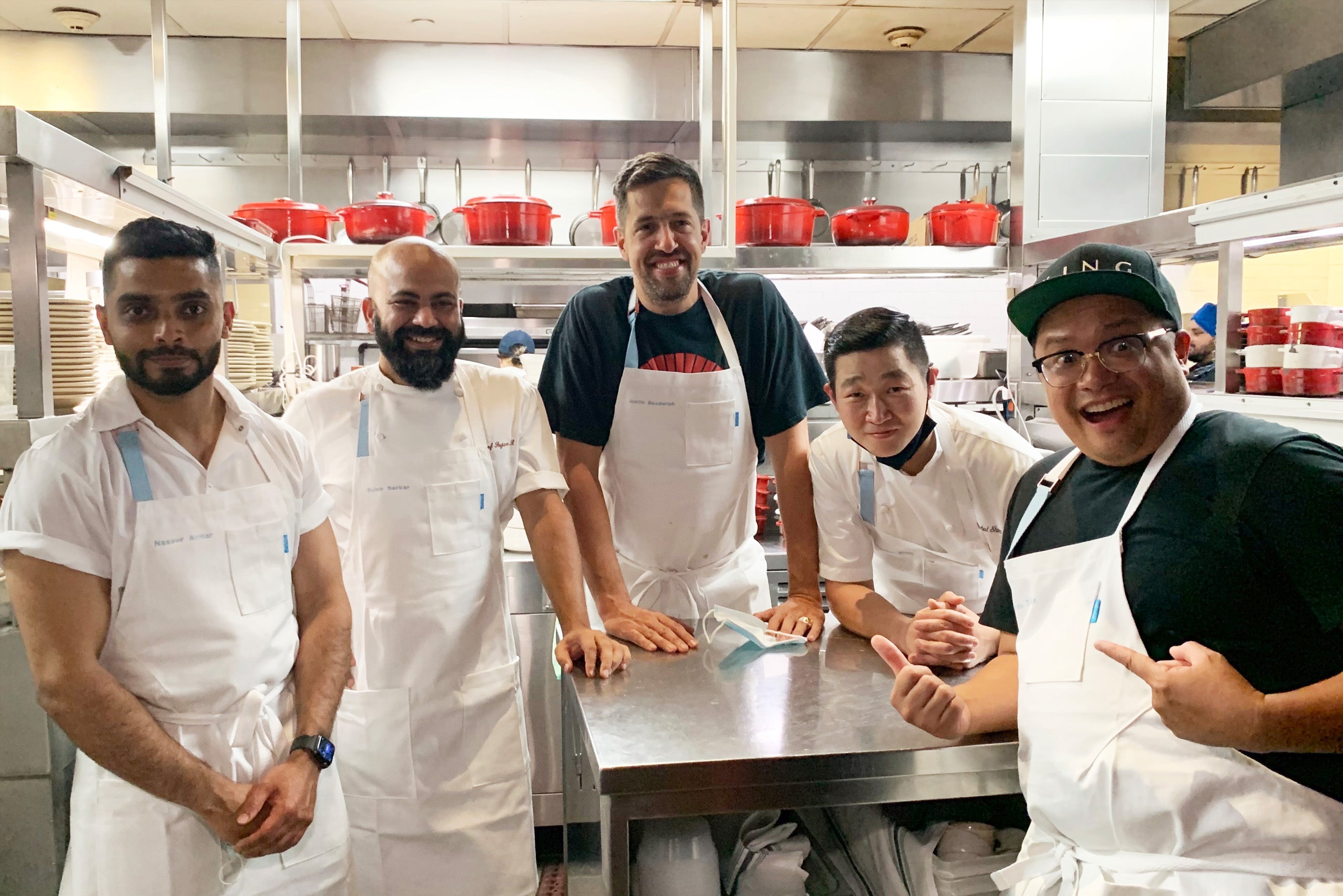 Five chefs wearing custom embroidered aprons in the kitchen