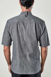 back view of a man wearing a charcoal chambray double-breasted chef coat.