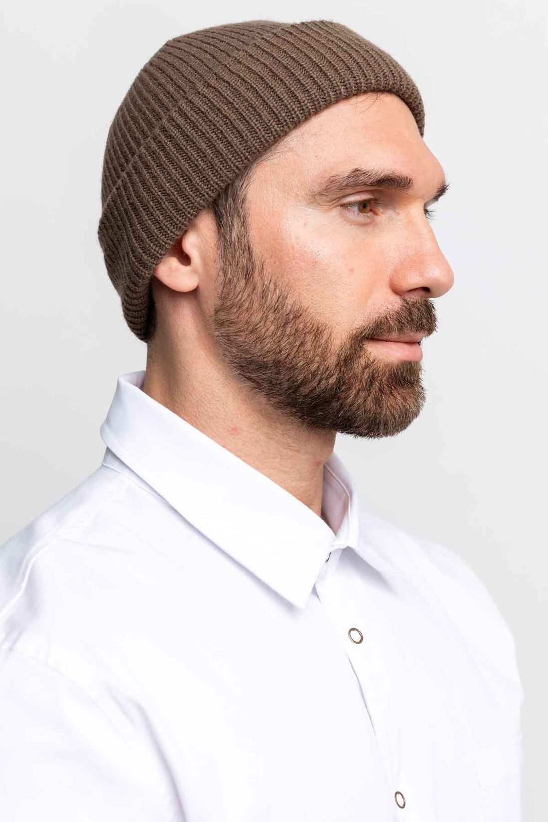Profile close-up of a man wearing a brown beanie.