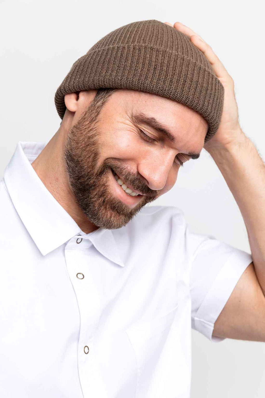 Profile close-up of a man wearing a brown beanie and smiling.
