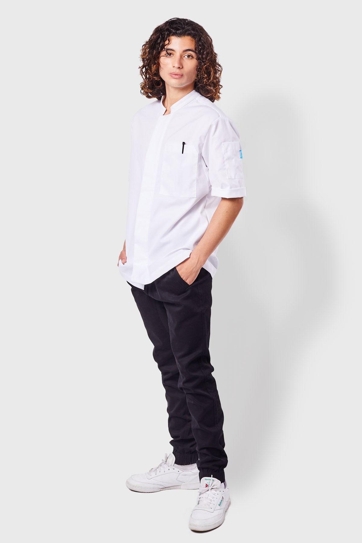 Man wearing black joggers and a white chef coat.