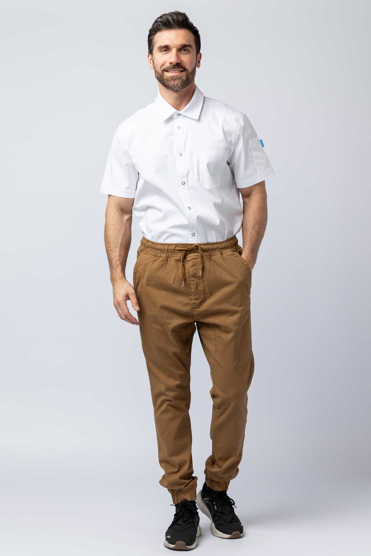 Man wearing khaki joggers and a white work shirt.