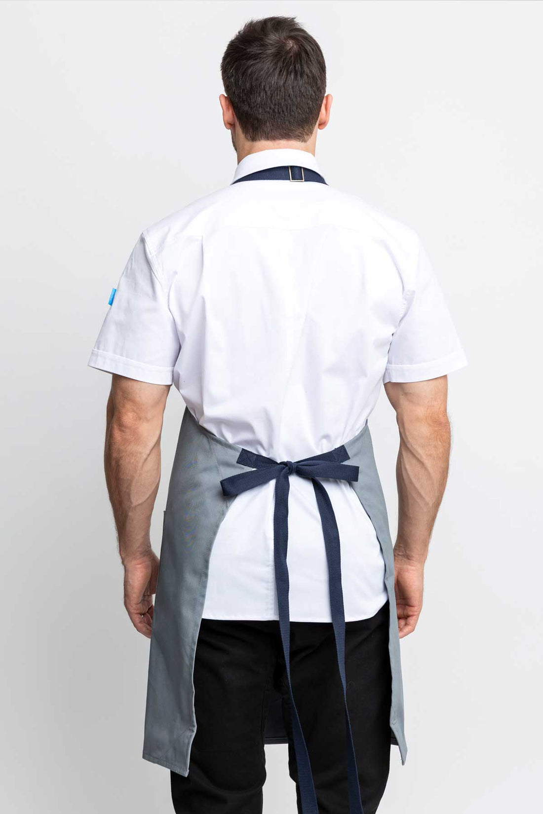 Back view of a man wearing an silver grey-colored denim apron