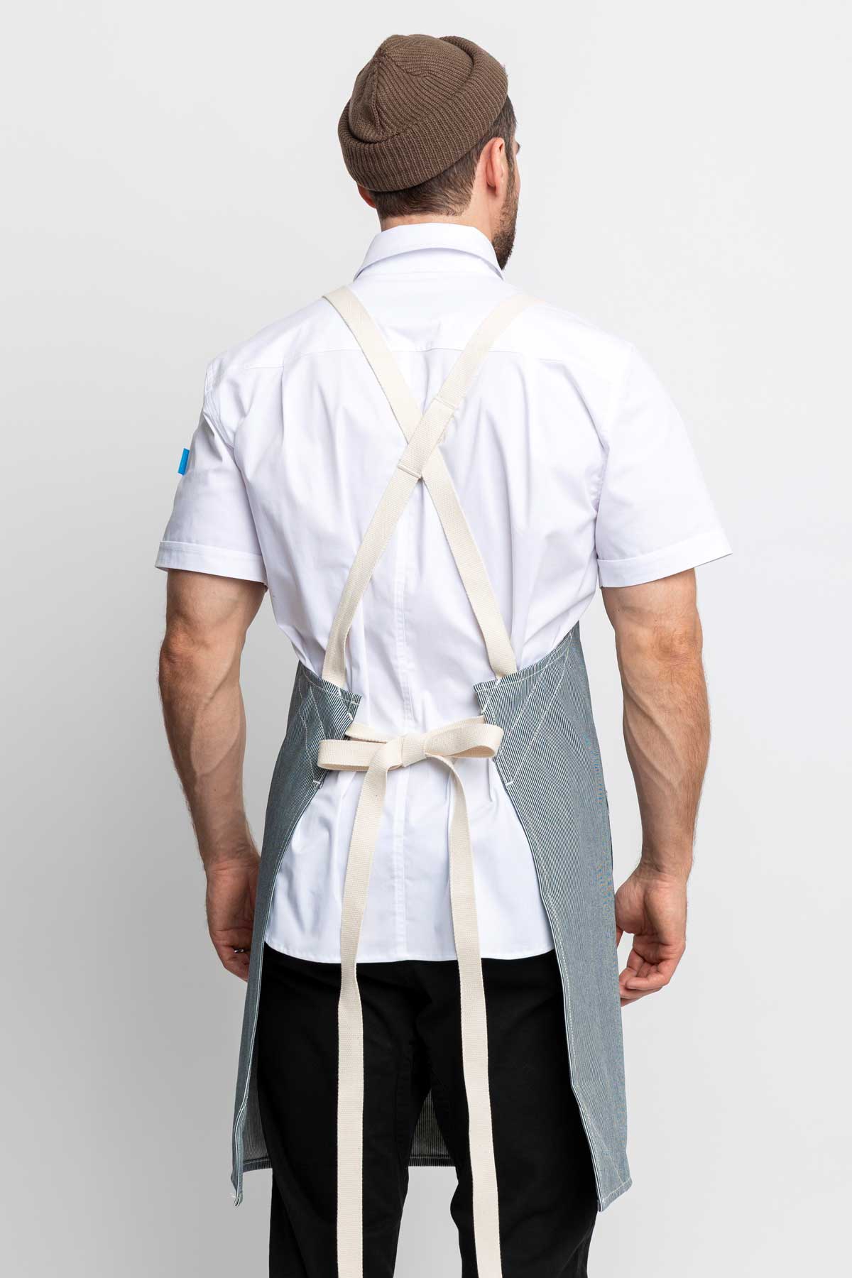 Back view of a man wearing a cross-back apron in railroad stripe denim