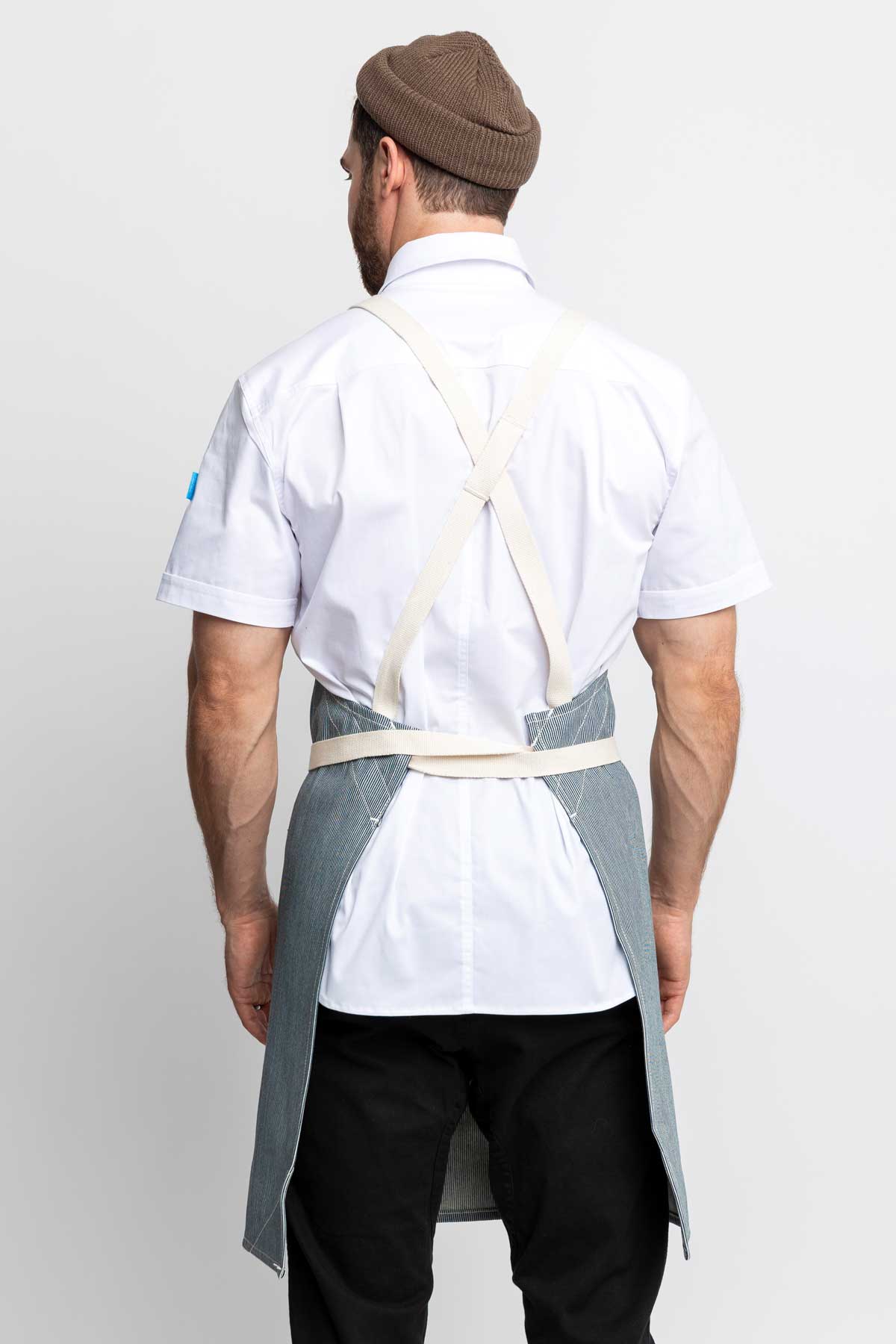 Back view of a man wearing a cross-back apron in railroad stripe denim