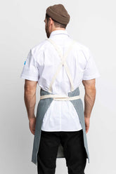 Back view of a man wearing a cross-back apron in railroad stripe denim