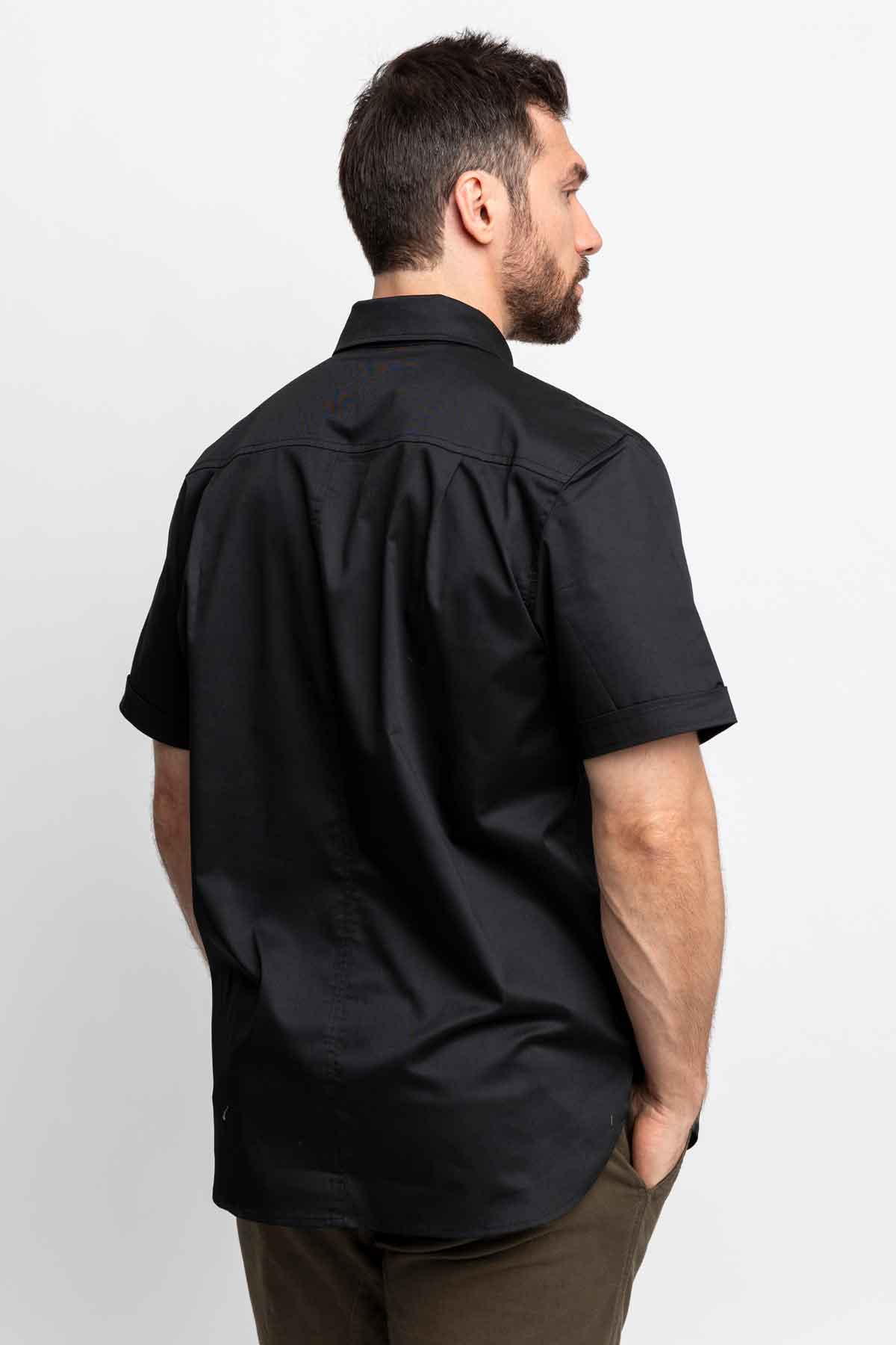 Three-quarter back view of men wearing black short-sleeve button-down shirts.