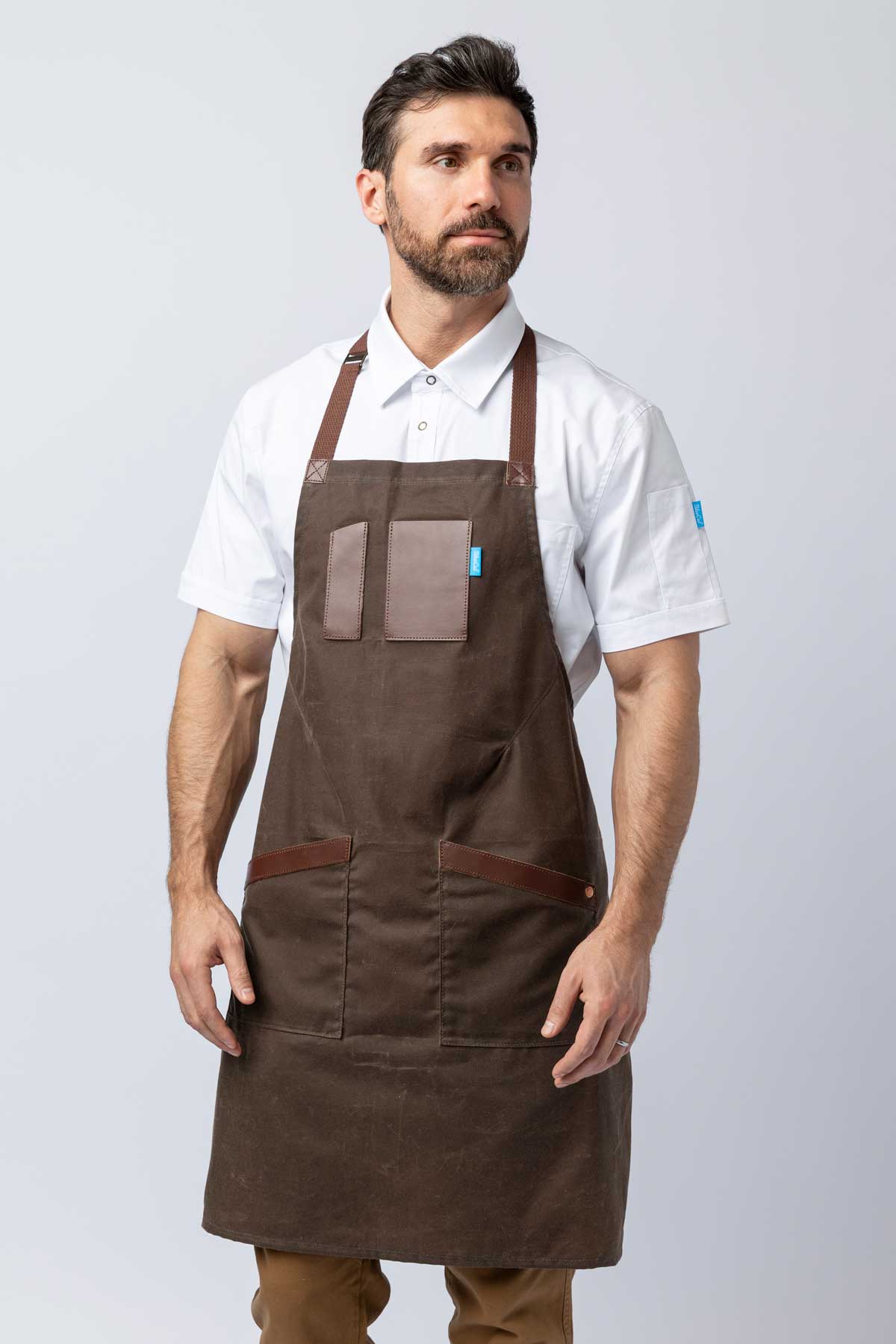 Man wearing a brown waxed canvas apron with leather accents.