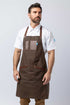 Man wearing a brown waxed canvas apron with leather accents.