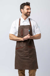 Man wearing a brown waxed canvas apron with leather accents.