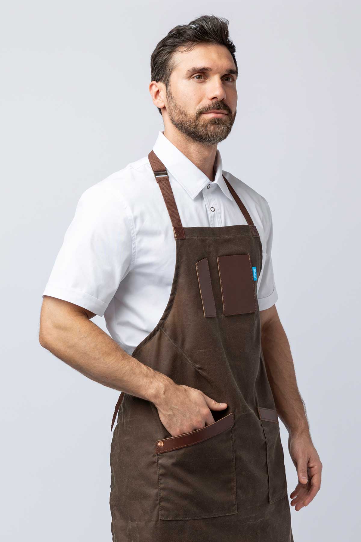 Man wearing a brown waxed canvas apron with leather accents.
