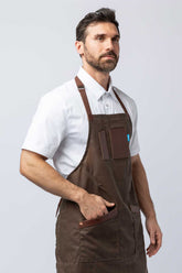 Man wearing a brown waxed canvas apron with leather accents.