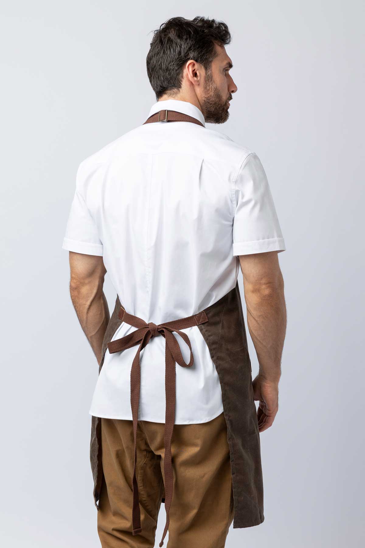 Rear view of a man wearing a brown waxed canvas apron.