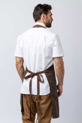 Rear view of a man wearing a brown waxed canvas apron.