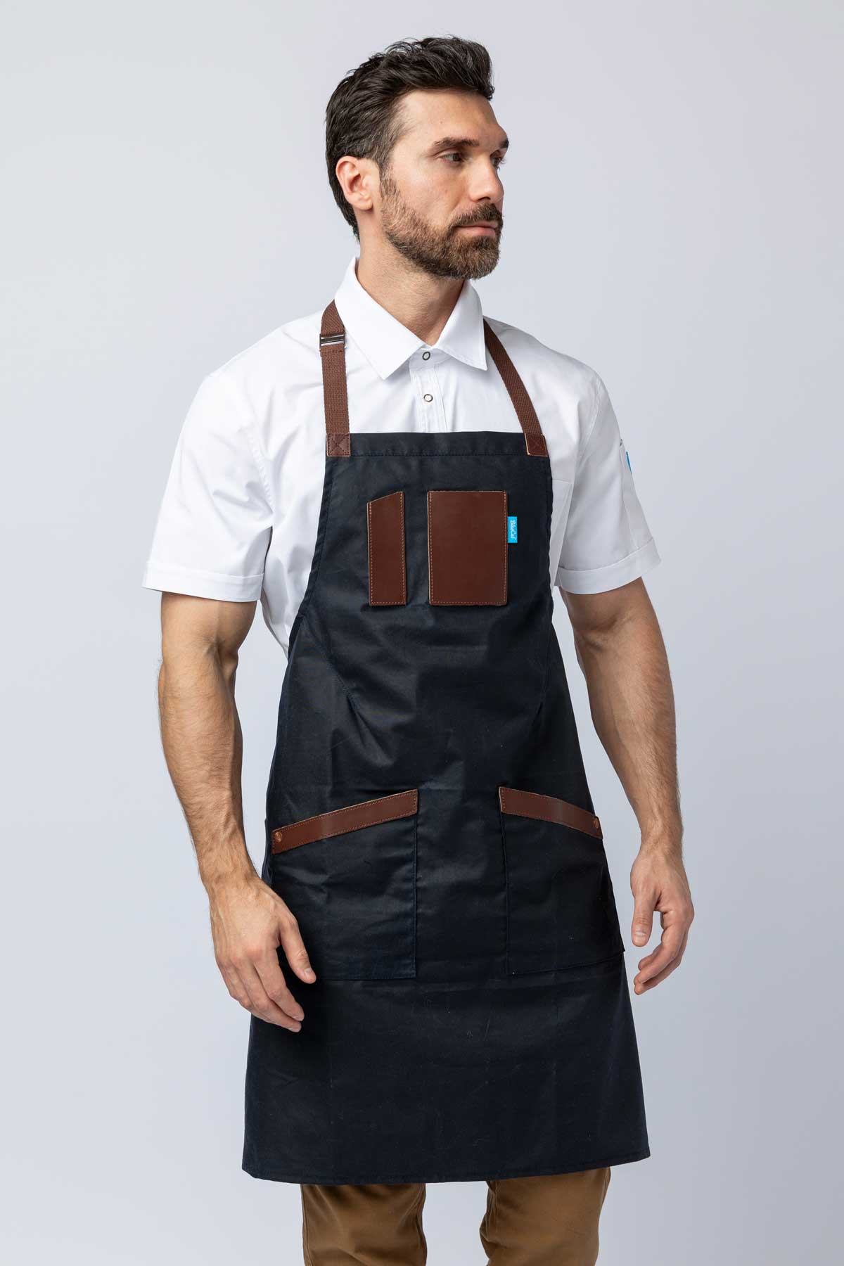 Man wearing a navy waxed canvas apron with leather accents.