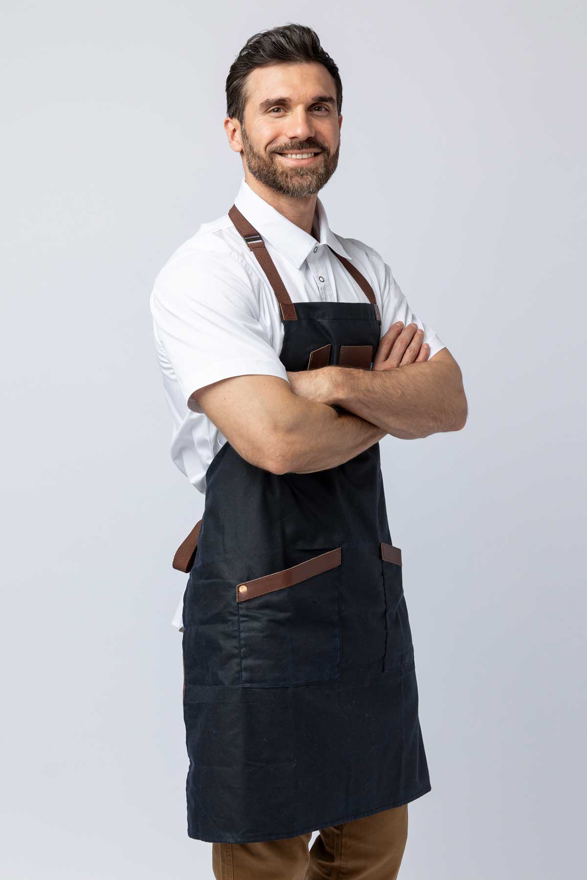 Man wearing a navy waxed canvas apron with leather accents.