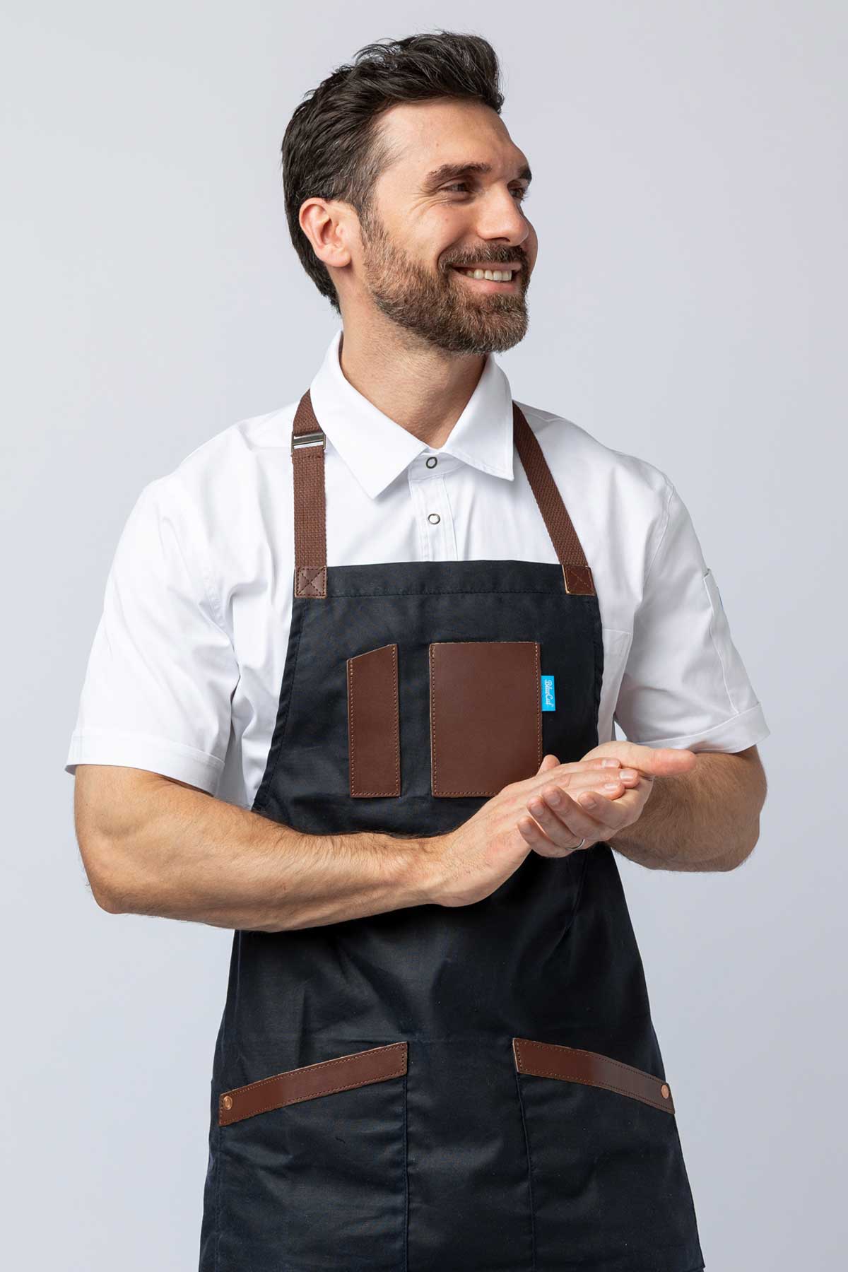 Man wearing a navy waxed canvas apron with leather accents.