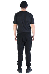Rear view of man wearing black joggers and a black t-shirt.