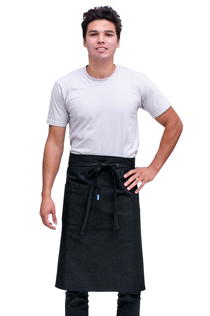 A man wearing a black bistro apron with pockets and a tie at the waist, standing in a relaxed pose.