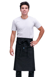 A man wearing a black bistro apron with pockets and a tie at the waist, standing in a relaxed pose.