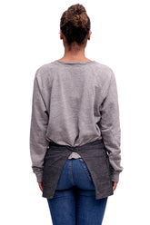 A back view of person wearing a charcoal mini denim apron standing against a neutral background.