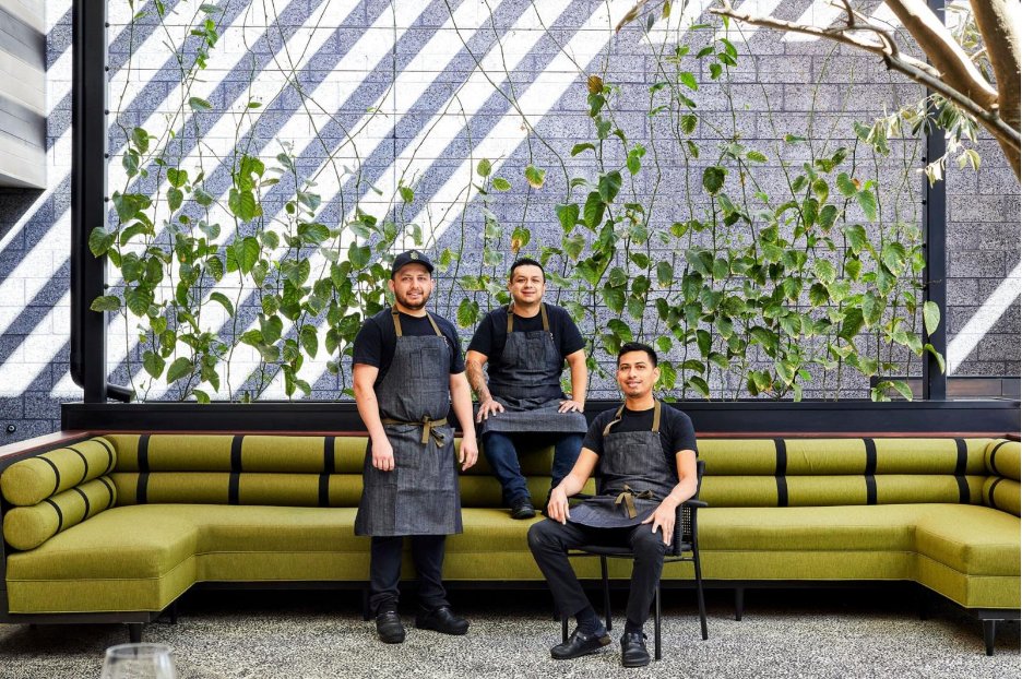 Three restaurant workers wearing black aprons. 