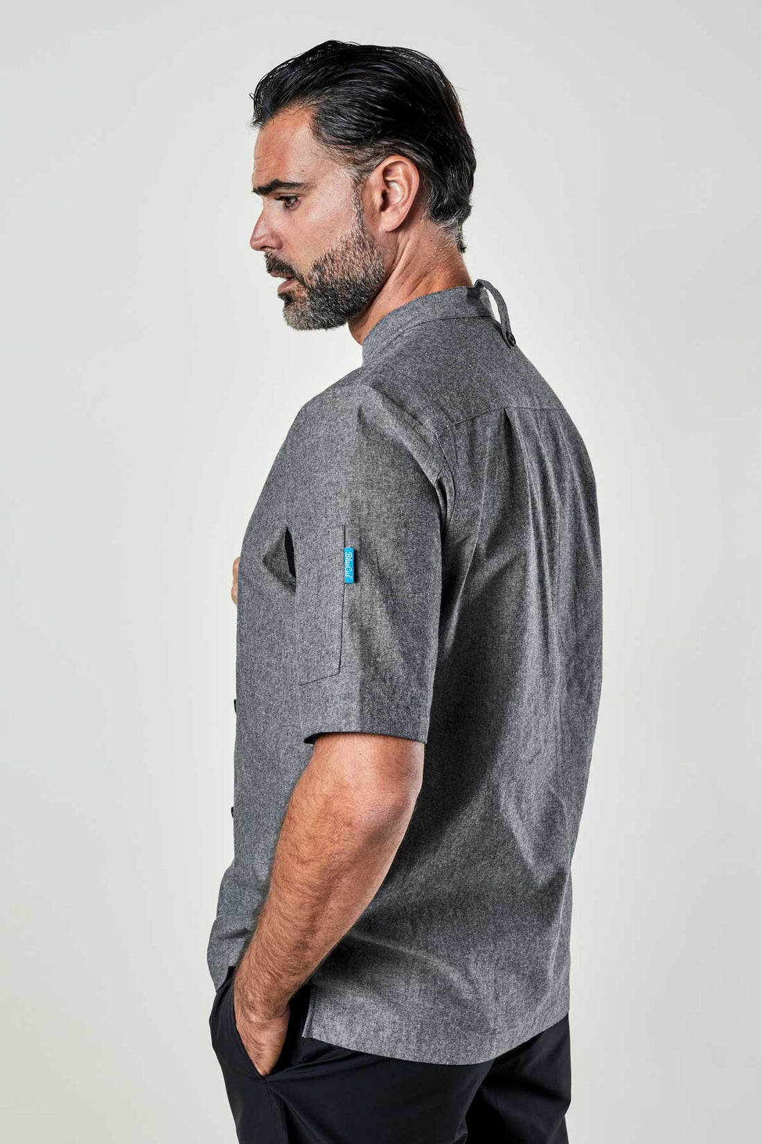 Side view of a man wearing a charcoal chambray double-breasted chef coat.