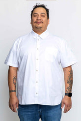 A plus size man wearing a white short-sleeved work shirt with a collar, chest pocket, and antique brass snap closures. -BlueCut Workwear