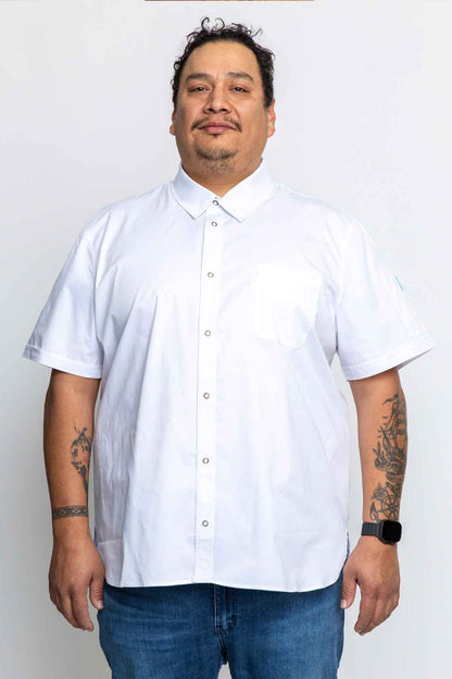 A plus size man wearing a white short-sleeved work shirt with a collar, chest pocket, and antique brass snap closures. -BlueCut Workwear