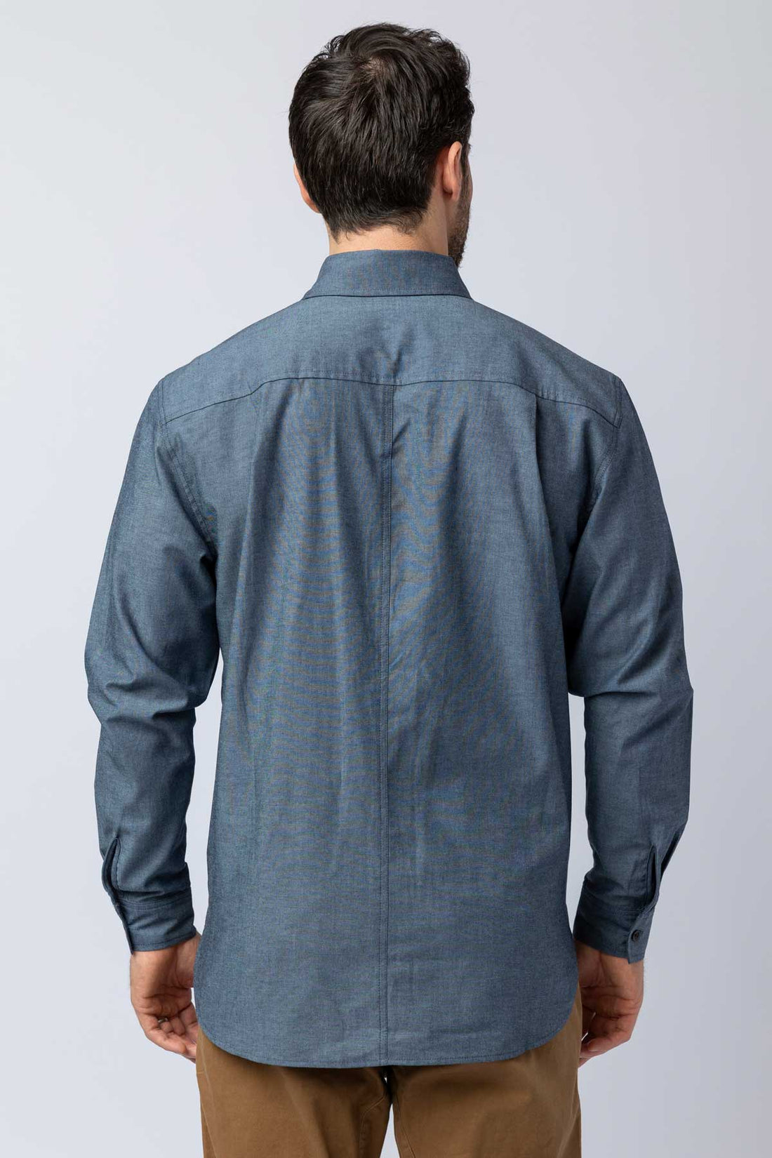 Rear view of men wearing blue long-sleeve chambray button-down shirts.