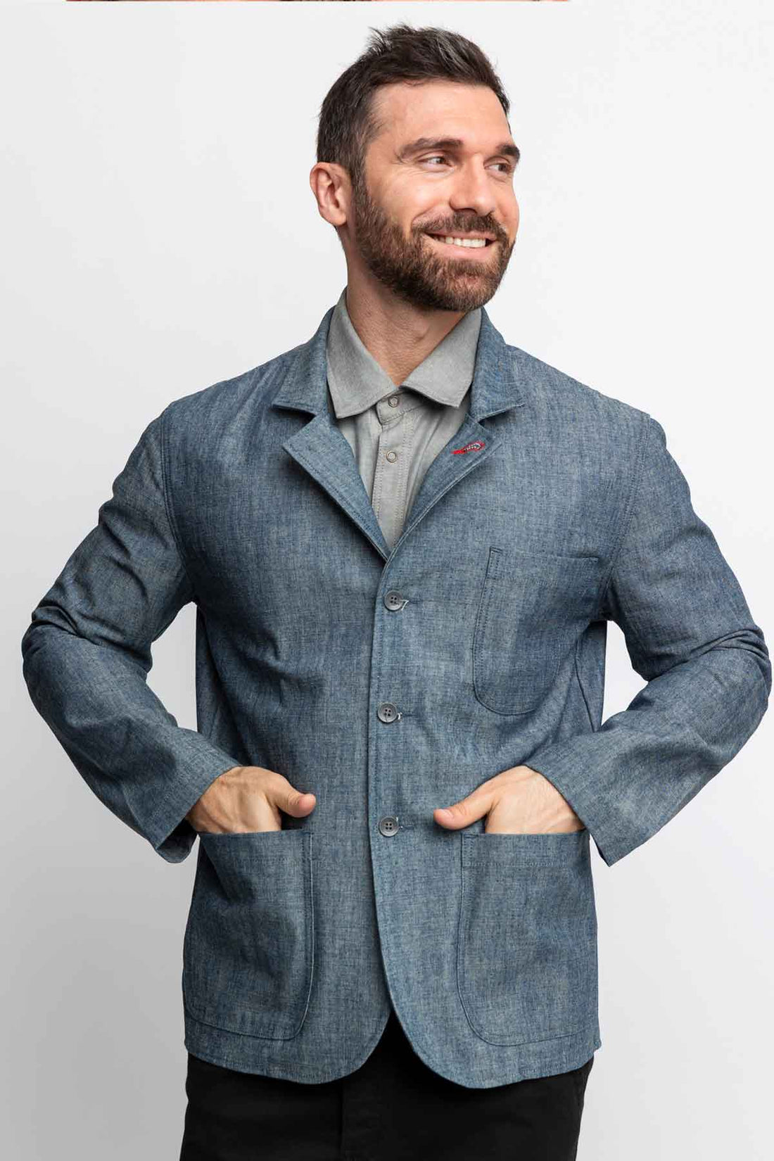 Front view of a man wearing a task jacket in blue chambray. 