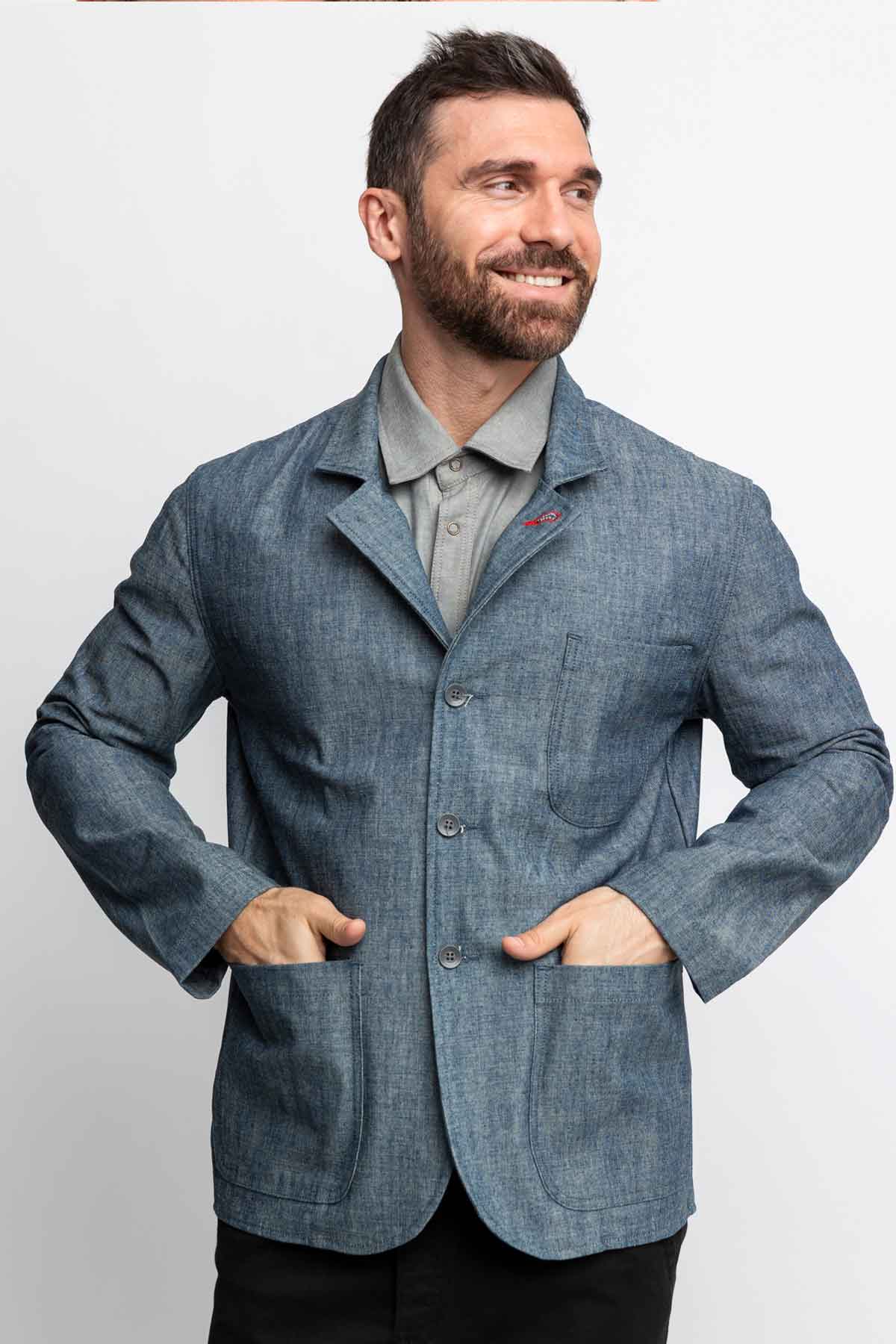 Front view of a man wearing a task jacket in blue chambray. 