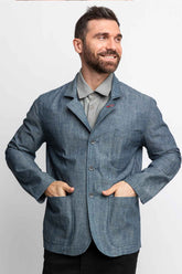 Front view of a man wearing a task jacket in blue chambray. 