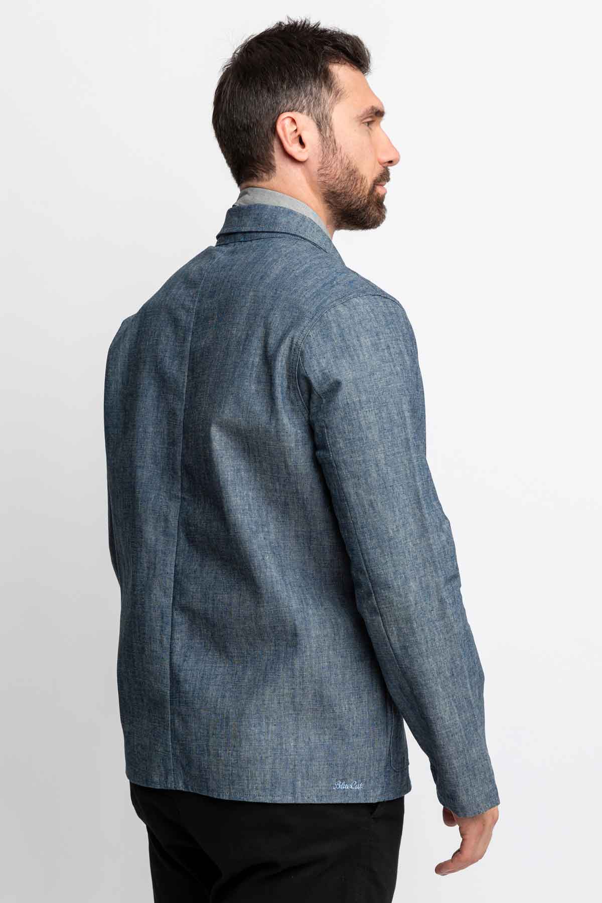 Three-quarter rear view of a man wearing a blue chambray task jacket.