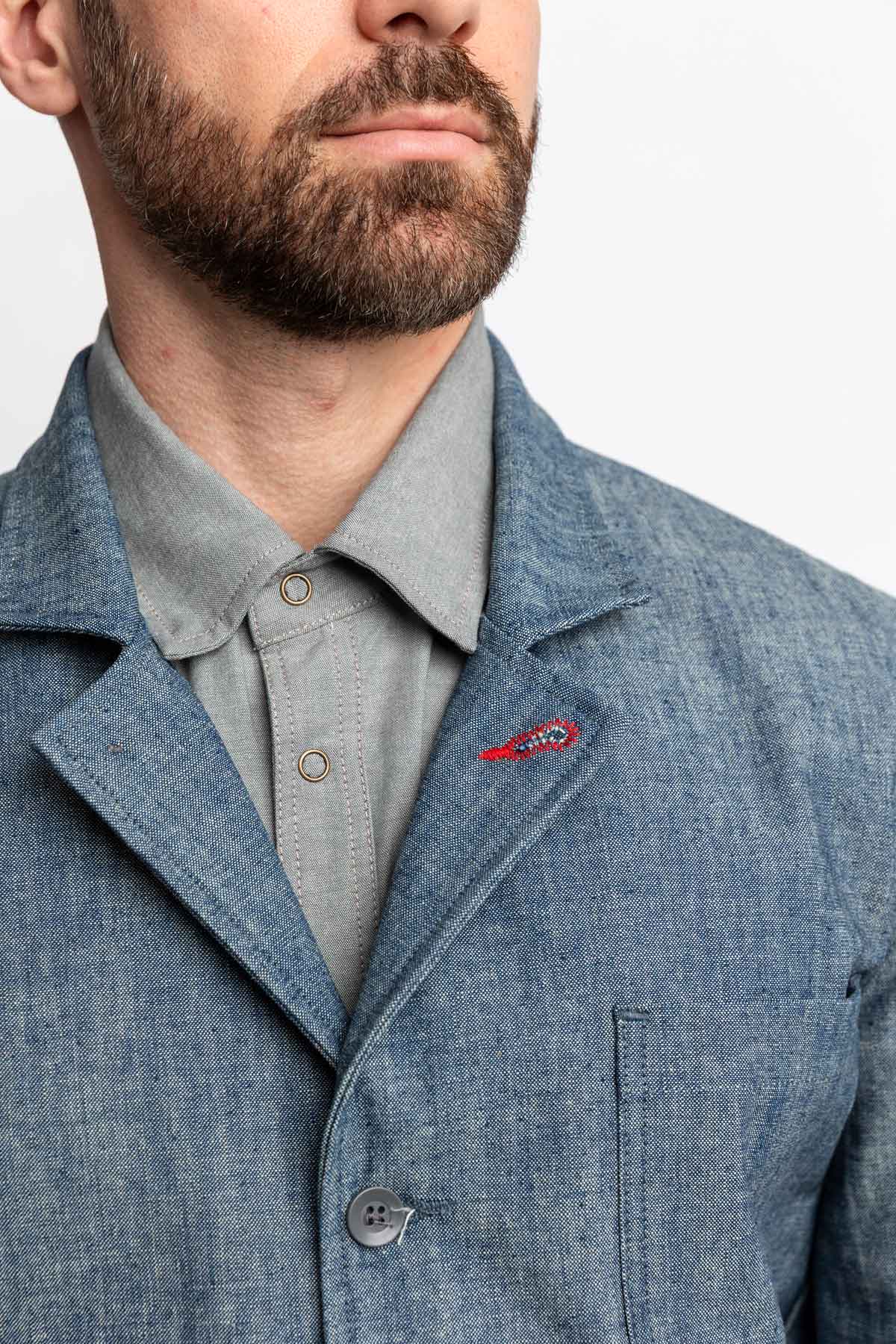 Detail view of a man wearing a task jacket in blue chambray.