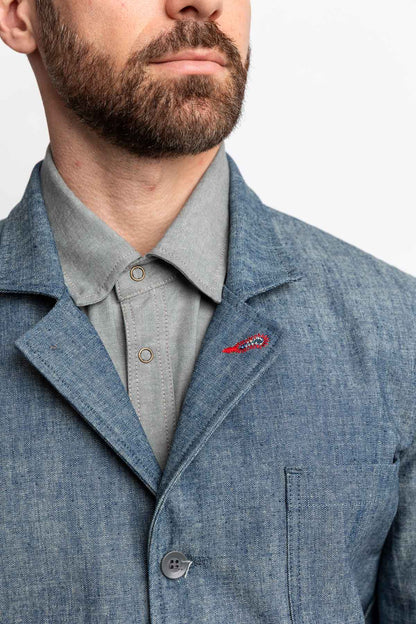 Detail view of a man wearing a task jacket in blue chambray.