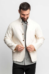 Man looking down while buttoning a natural-colored task jacket.