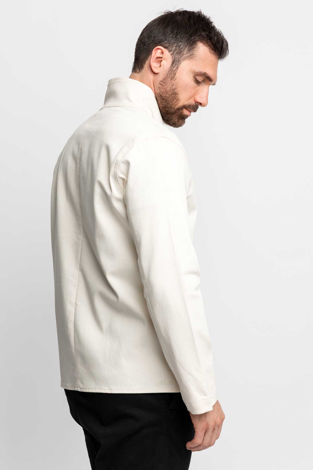 Three-quarter rear view of a man wearing a natural-colored task jacket.