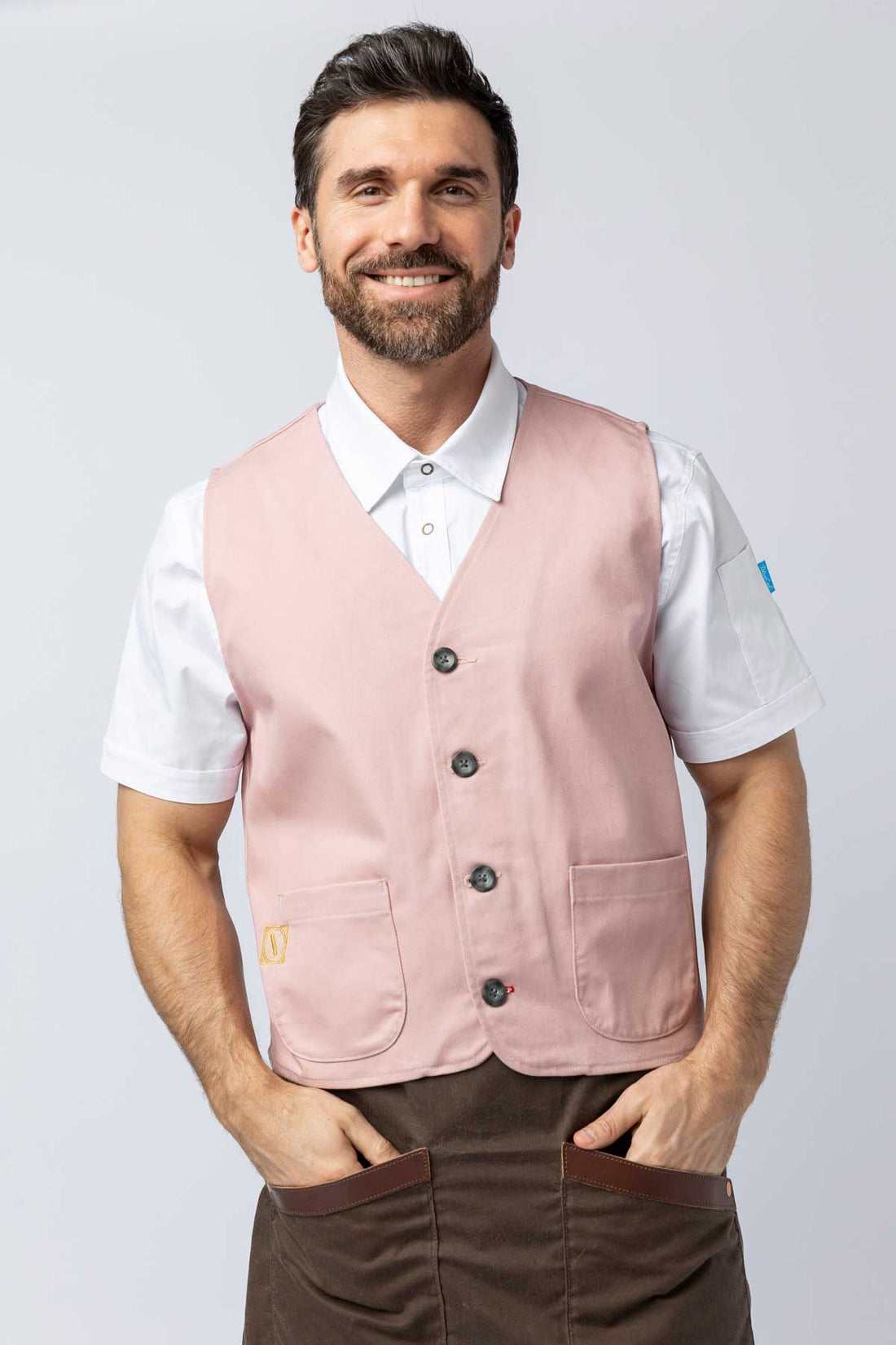 Man wearing a pink vest over a white shirt on a light gray background